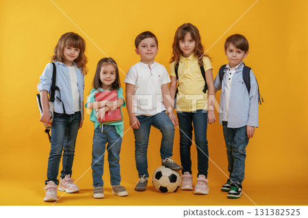 Standing and posing. Kids are together against yellow background 131382525