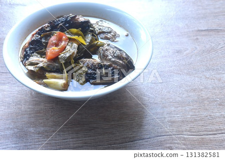 boiled smoked dry snake head fish with tamarind leaf in spicy and sour soup on bowl boiled smoked dry snake head fish with tamarind leaf in spicy and sour soup on bowl 131382581