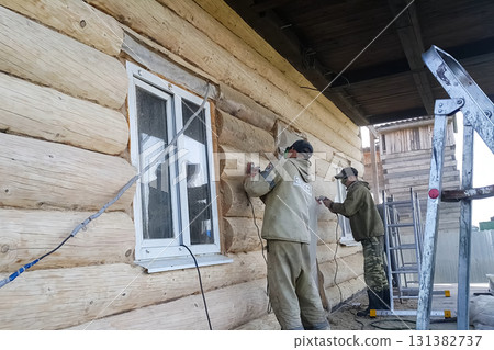 Workers clean logs from blackened wood by grinding Workers clean logs from blackened wood by grinding 131382737
