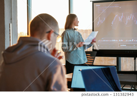 Guy is listening. Female business trainer is against projector with business data, teaching the man Guy is listening. Female business trainer is against projector with business data, teaching the man 131382943