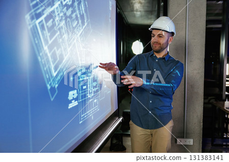 Modern exterior. Man architect in hard hat is near projector with construction plan Modern exterior. Man architect in hard hat is near projector with construction plan 131383141