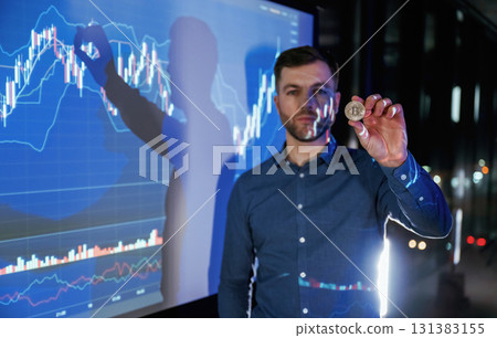 Digital currency, holding coin in hand. Business coach against projector with data Digital currency, holding coin in hand. Business coach against projector with data 131383155