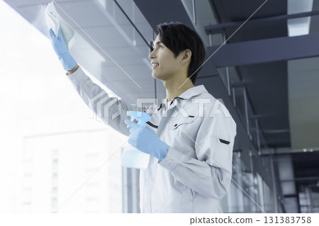 一名年輕的男清潔工正在清潔窗戶。 131383758