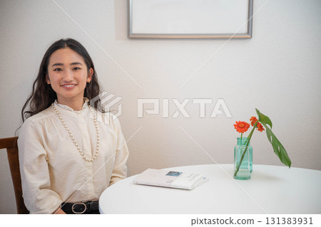 一位長髮年輕女子坐在室內的桌子旁大笑 一位長髮年輕女子坐在室內的桌子旁大笑 131383931