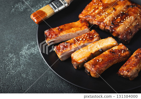 Hot grilled spare ribs from a summer BBQ served on a plate with sauce. Top view. Copy space 131384000