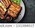 Hot grilled spare ribs from a summer BBQ served on a plate with sauce. Top view. Copy space 131384017