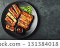 Hot grilled spare ribs from a summer BBQ served on a plate with sauce. Top view. Copy space 131384018