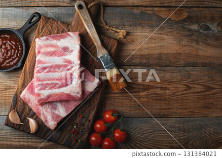 Raw pork ribs with spices, salt and rosemary on dark wooden background 131384021