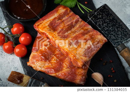 Ready for BBQ raw pork spare ribs with barbecue sauce. Black background. Top view 131384035