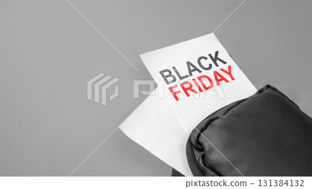 Closeup view of Black Friday text on white paper from the bag on a gray background. Copy space. Black Friday sale concept 131384132