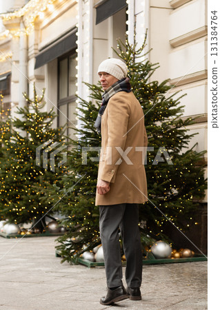 Adult caucasian man going to luxury store for shopping. Xmas holiday. Wearing warm clothing. Festive street with Christmas decorations. Adult caucasian man going to luxury store for shopping. Xmas holiday. Wearing warm clothing. Festive street with Christmas decorations. 131384764
