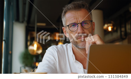 Professional man working remotely in a cozy cafe setting during the daytime Professional man working remotely in a cozy cafe setting during the daytime 131384849