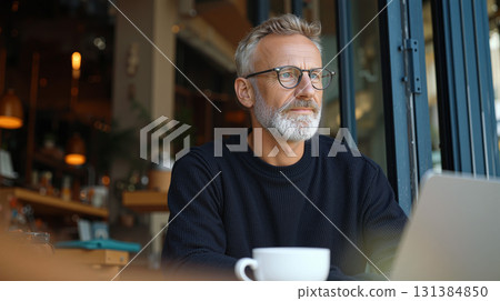 Professional man works remotely in a cozy cafe while enjoying a cup of coffee on a sunny day 131384850