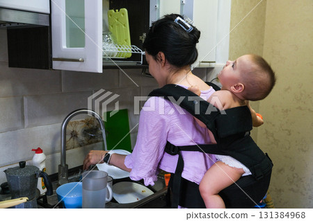 Mother Washing Dishes with Baby on Her Back Mother Washing Dishes with Baby on Her Back 131384968