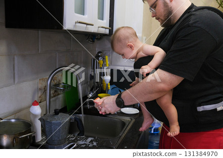 Father Washing Dishes with Baby in Carrier Father Washing Dishes with Baby in Carrier 131384970