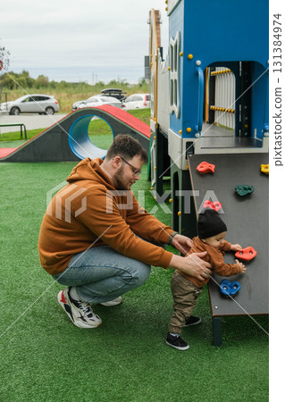 Father Assisting Toddler on Playground Climbing Wall Father Assisting Toddler on Playground Climbing Wall 131384974
