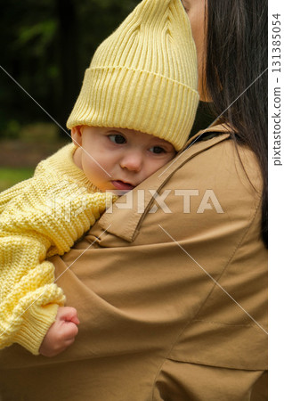 Mother Holding Baby in Yellow Outfit at Park Mother Holding Baby in Yellow Outfit at Park 131385054