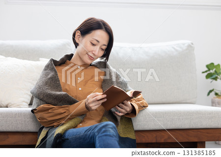 Middle-aged woman enjoying reading in the living room at home 131385185