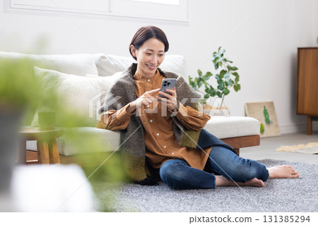 Middle woman operating a smartphone in the living room 131385294