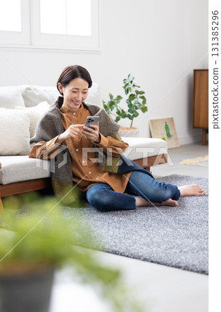 Middle woman operating a smartphone in the living room 131385296