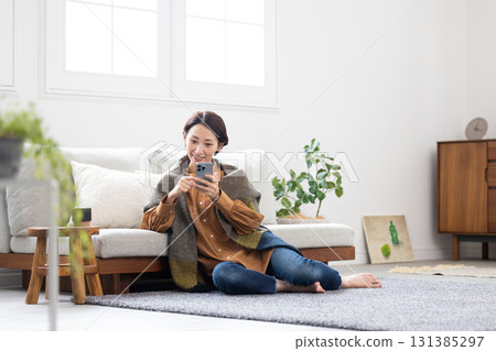 Middle woman operating a smartphone in the living room Middle woman operating a smartphone in the living room 131385297