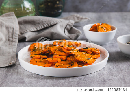 Pieces of fried carrots with garlic and herbs on a plate on the table Pieces of fried carrots with garlic and herbs on a plate on the table 131385484