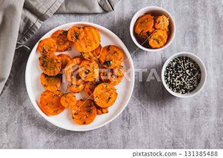 Pieces of fried carrots with garlic and herbs on a plate on the table top view 131385488