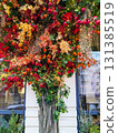 Exterior holiday decoration featuring a vibrant tree with red berries, golden leaves, glowing string lights, autumn foliage, and cozy seasonal atmosphere 131385519