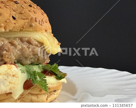 A large cheeseburger with tomatoes and greens on a white plate. Delicious, nutritious, and quick food. 131385657