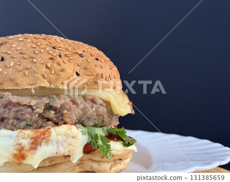 A large cheeseburger with tomatoes and greens on a white plate. Delicious, nutritious, and quick food. 131385659
