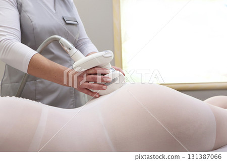 Lpg massage procedure. Special underwear for figure correction. The doctor's hands holding the lipomassage tool. Close-up, selective focus. Lpg massage procedure. Special underwear for figure correction. The doctor's hands holding the lipomassage tool. Close-up, selective focus. 131387066