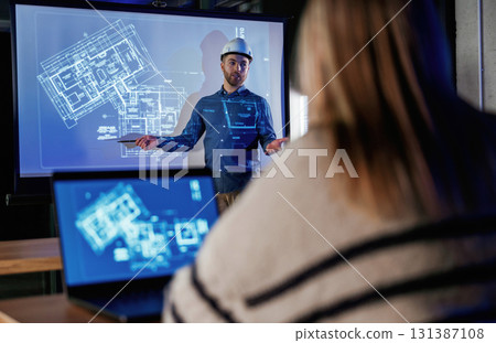 Male architect is showing construction site project on blue projector for people 131387108