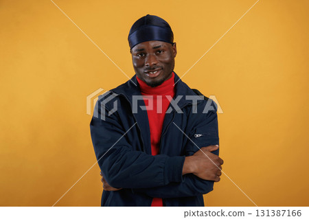 Cheerful facial expression. Handsome black man is in the studio against yellow background 131387166