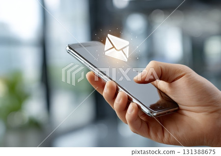 Hand holding smartphone displaying glowing email icon, representing digital marketing concept 131388675