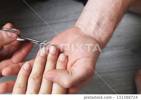 A guy does a manicure for a girl. cuts off the nails and cuticles on the fingernails A guy does a manicure for a girl. cuts off the nails and cuticles on the fingernails 131388724