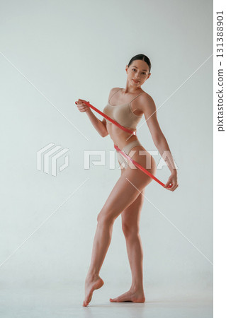 With measuring tape. Woman with slim body shape is posing against background With measuring tape. Woman with slim body shape is posing against background 131388901