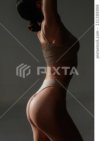 In the dark. Woman with slim body shape is posing against background In the dark. Woman with slim body shape is posing against background 131388908