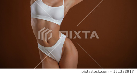 Front view. Woman with slim body shape is posing against background Front view. Woman with slim body shape is posing against background 131388917