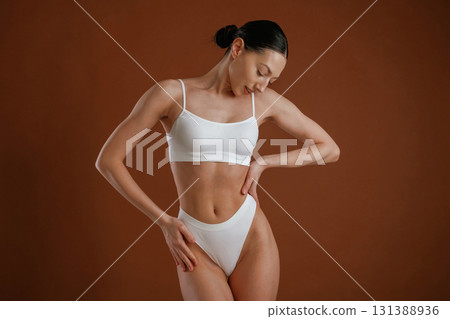 New underwear collection. Woman with slim body shape is posing against background New underwear collection. Woman with slim body shape is posing against background 131388936