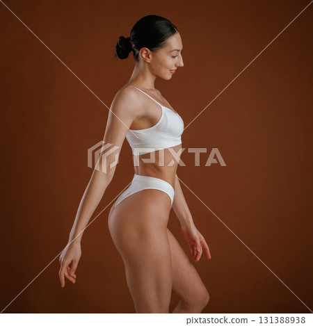New underwear collection. Woman with slim body shape is posing against background New underwear collection. Woman with slim body shape is posing against background 131388938