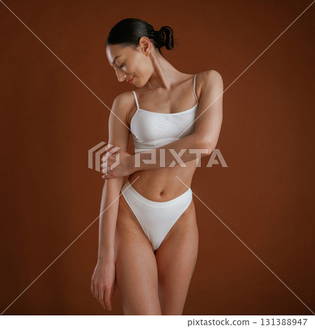 Showing brand new underwear. Woman with slim body shape is posing against background Showing brand new underwear. Woman with slim body shape is posing against background 131388947