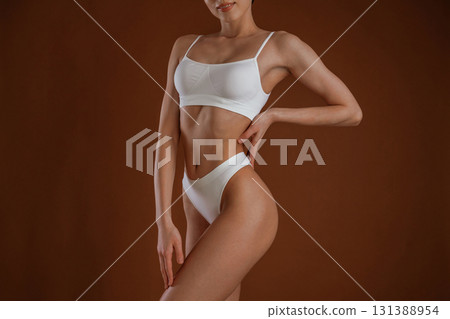 Professional photoshoot. Woman with slim body shape is posing against background Professional photoshoot. Woman with slim body shape is posing against background 131388954