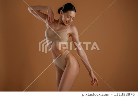 Creamy colored underwear. Woman with slim body shape is posing against background Creamy colored underwear. Woman with slim body shape is posing against background 131388976