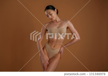 Creamy colored underwear. Woman with slim body shape is posing against background Creamy colored underwear. Woman with slim body shape is posing against background 131388978