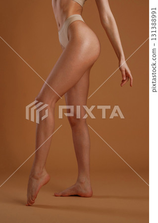 Showing the side, standing. Woman with slim body shape is posing against background 131388991