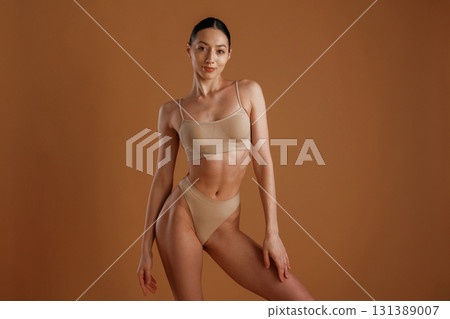 Skinny girl. Woman with slim body shape is posing against background Skinny girl. Woman with slim body shape is posing against background 131389007