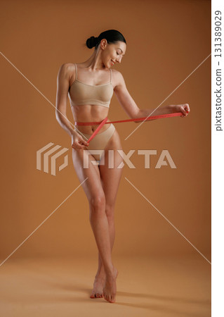 Successful weight loss, diet. Woman with slim body shape is posing against background Successful weight loss, diet. Woman with slim body shape is posing against background 131389029