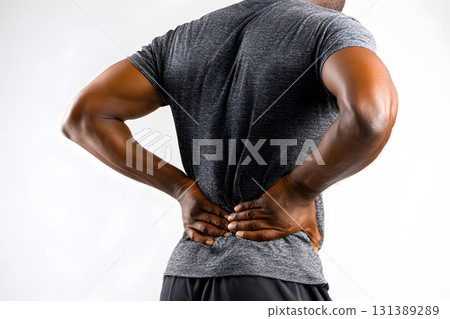 Person holds aching lower back in pain. 131389289