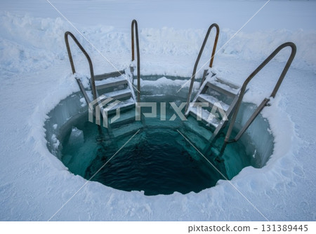 Cold plunge ice bath therapy setup with metal stairs surrounded by snow and ice for wellness benefits 131389445