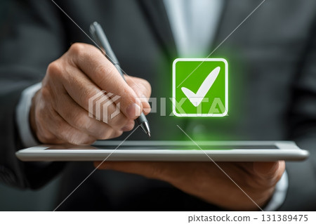 Business person signs approval on tablet screen with check mark. 131389475